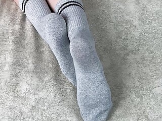 Girl in bed strokes her legs in gray cotton socks